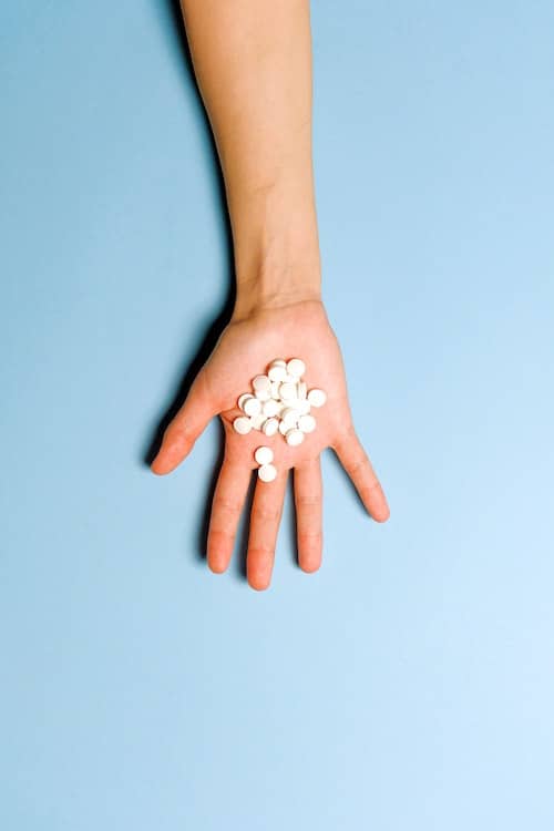 open palm holding a bunch of white round pills